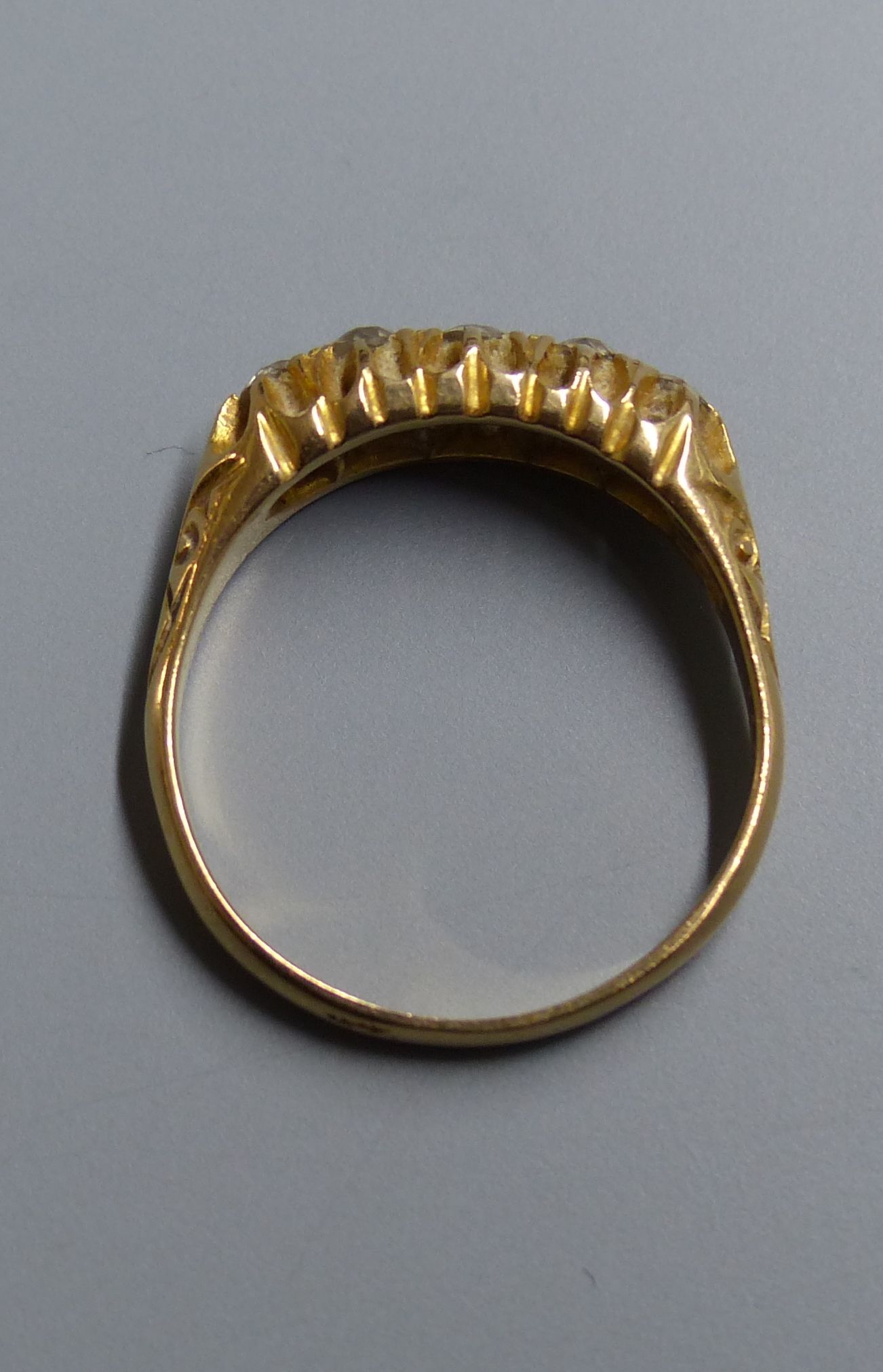 An Edwardian 18ct gold and graduated five stone diamond set half hoop ring, size P/Q, gross 4 grams.